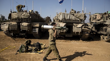 An Israeli soldier carries a tank shell after returning from the Gaza Strip
