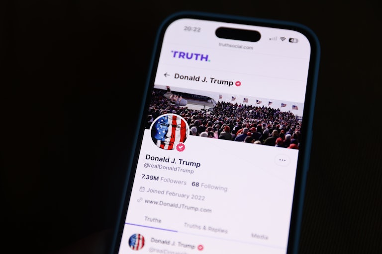A phone screen displays Donald Trump’s Truth Social account