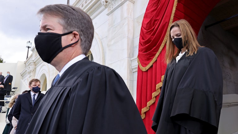 A masked Brett Kavanaugh is trailed by a masked Amy Coney Barrett as the two Justices make their way to their seats.