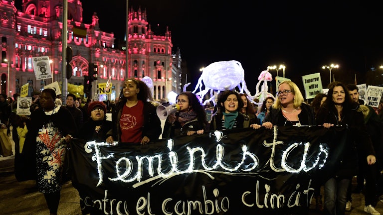 Activists walk holding a banner.