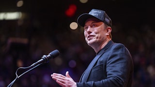 Elon Musk gestures while standing at a podium