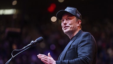 Elon Musk gestures while standing at a podium