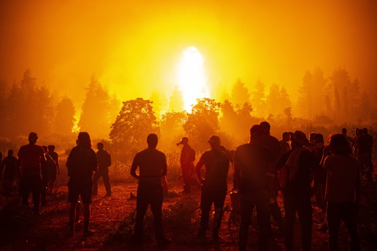 People stand in front of a raging wildfire.