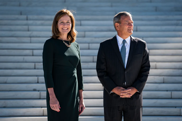 Justice Amy Coney Barrett and Chief Justice John Roberts stand on the steps of the Supreme Court.