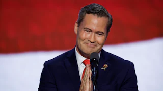 Mike Waltz clasps his hands together in front of a microphone.