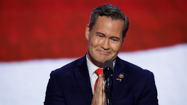 Mike Waltz clasps his hands together in front of a microphone.