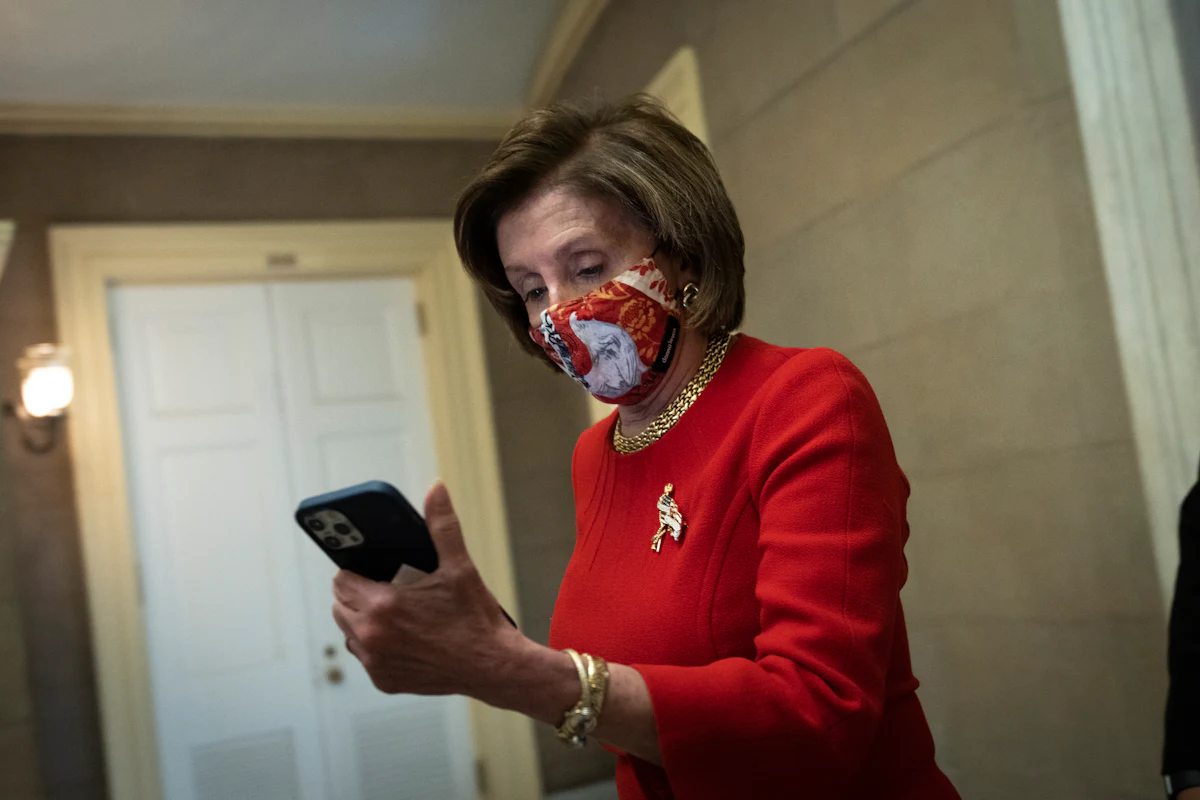 Democratic House Speaker Nancy Pelosi looks at her phone as she returns to her office on Capitol Hill.