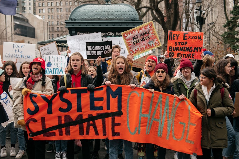Young climate activists hold signs and chant at City Hall in New York City.