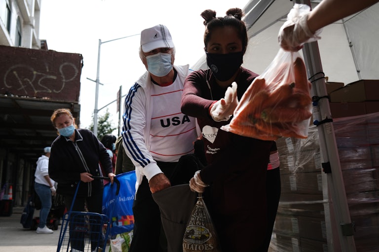 A masked couple collects carrots at a food bank. 