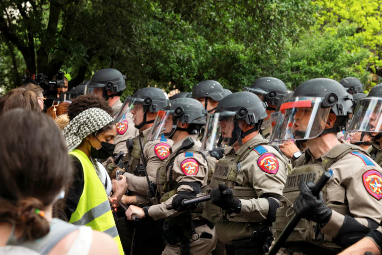 Police officers stand opposite protesters