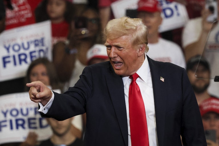 Donald Trump smiles and points at the crowd at a campaign rally