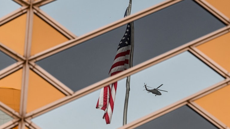 The American flag is reflected on the windows of the U.S. embassy building in Kabul as a helicopter flies away.