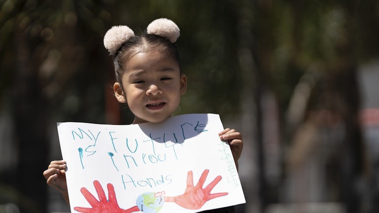 A child holds up a sign saying "my future is in your hands."