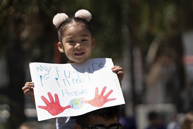 A child holds up a sign saying "my future is in your hands."