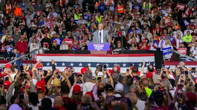 RFK Jr. stands at a podium surrounded by fans.