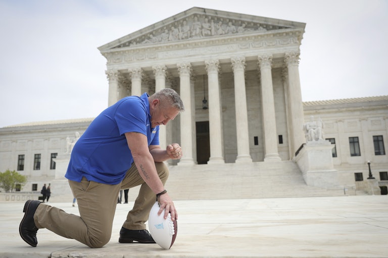 Former Bremerton High School assistant football coach Joe Kennedy takes a knee in front of the U.S. Supreme Court after his legal case, Kennedy vs. Bremerton School District, was argued before the court.