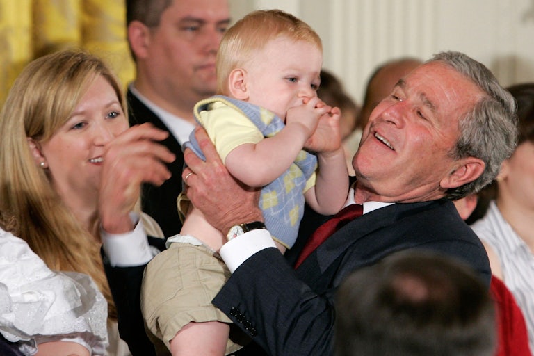 President George W. Bush holds a child after speaking about his veto of a stem cell research bill during a ceremony in the East Room at the White House on July 19, 2006.