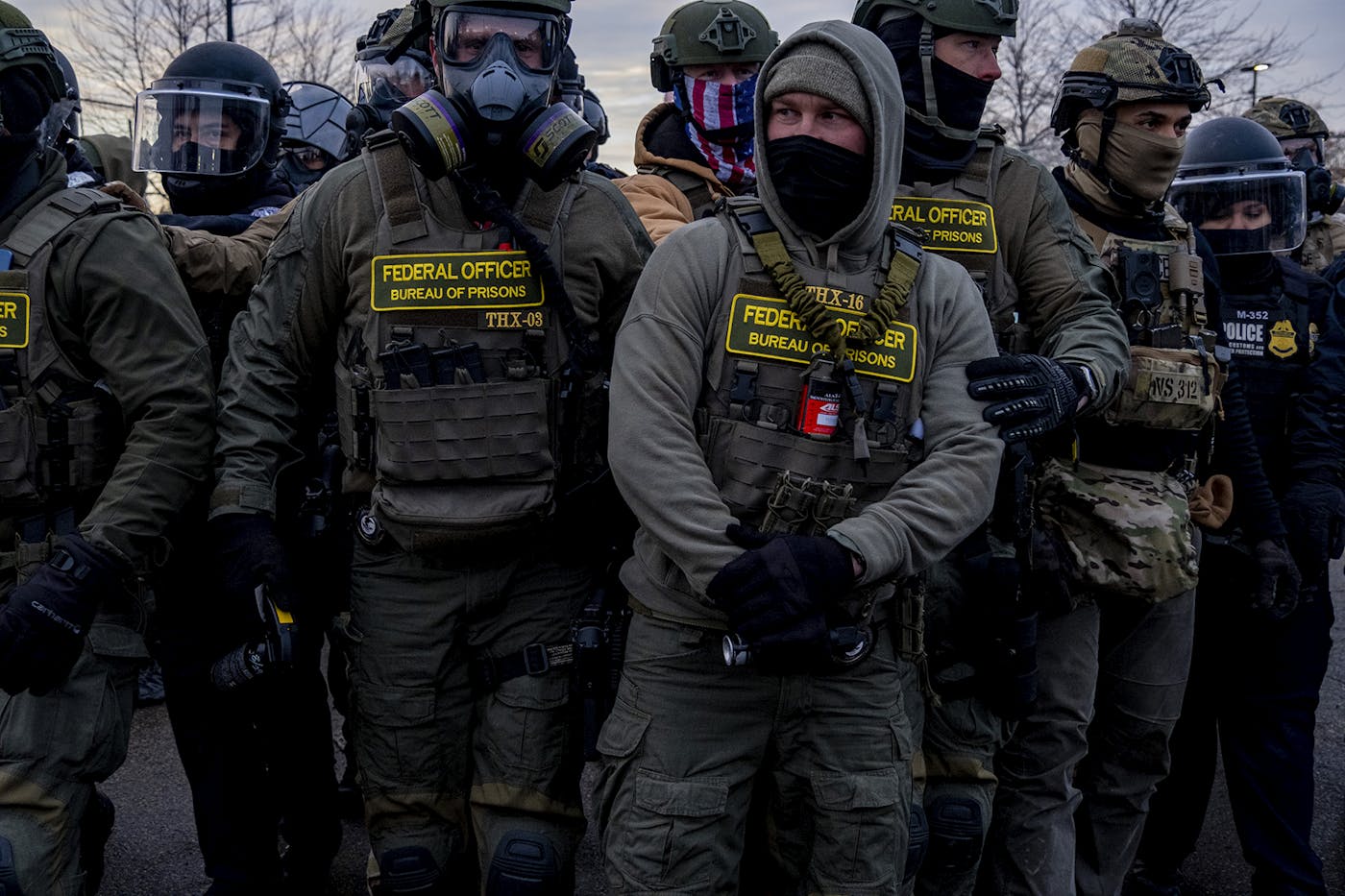 ICE agents, faces masked, gather outside the Bishop Henry Whipple Federal Building.