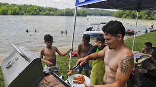 Rafael Burgos works the grill at his family's spot by Blue Marsh Lake in Pennsylvania on Fourth of July weekend in 2020.