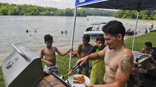 Rafael Burgos works the grill at his family's spot by Blue Marsh Lake in Pennsylvania on Fourth of July weekend in 2020. 