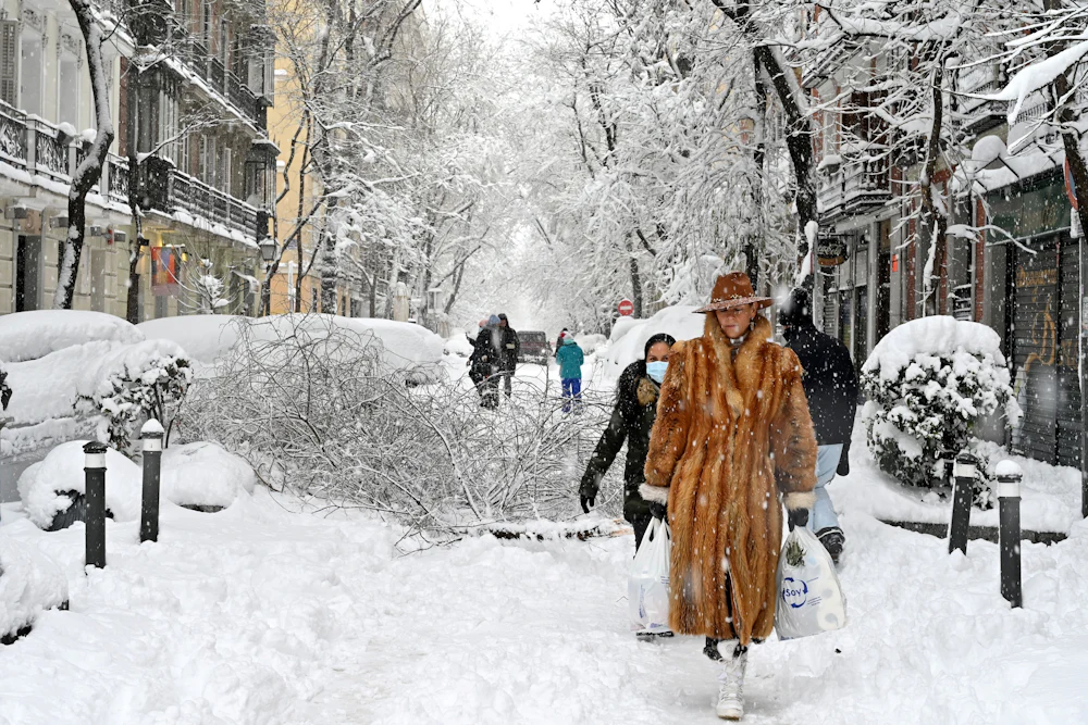 A woman wearing a fur coat walks amid a heavy snowfall in Madrid in January 2021.