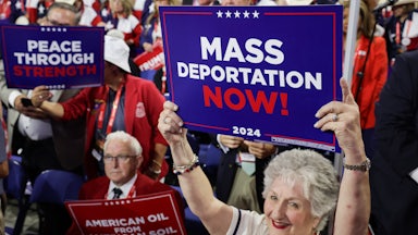 People hold signs that read "Mass Deportation Now!" on the third day of the Republican National Convention at the Fiserv Forum on July 17, 2024 in Milwaukee, Wisconsin.