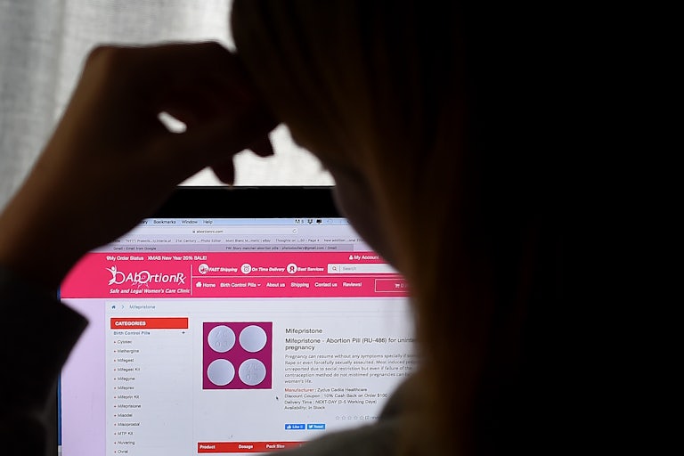 A person looks at an Abortion Pill (RU-486) for unintended pregnancy from Mifepristone displayed on a computer.