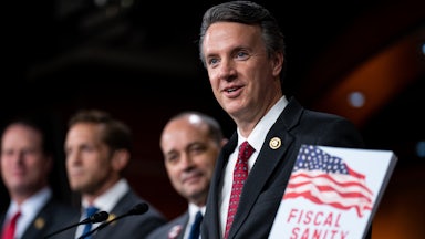 Representative Ben Cline holds up a packet labeled “Fiscal Sanity” while speaking at a microphone