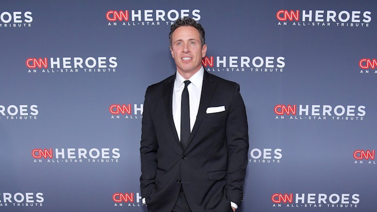 CNN anchor Chris Cuomo stands before a backdrop advertising the network's programming.