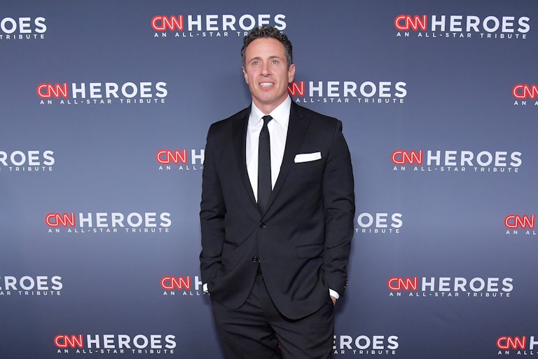 CNN anchor Chris Cuomo stands before a backdrop advertising the network's programming.