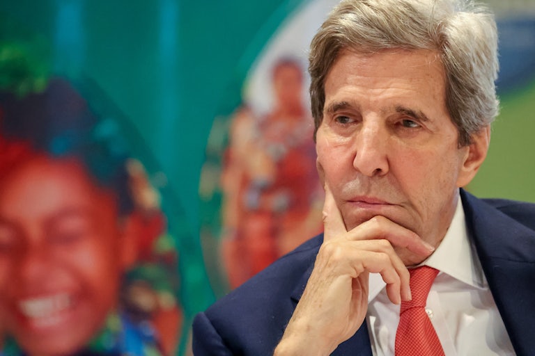 John Kerry sits with his head on his chin, looking contemplative.
