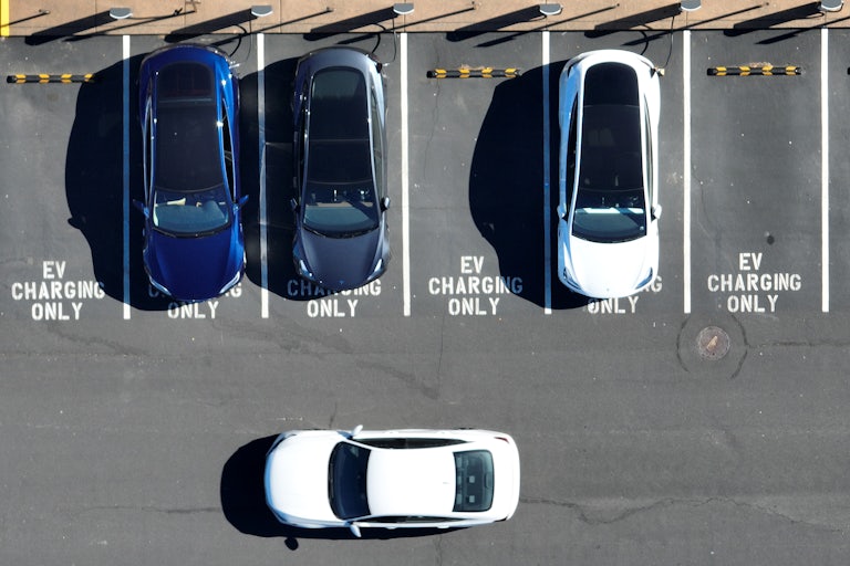 An aerial view of cars pulling in and out of an EV charging lot.