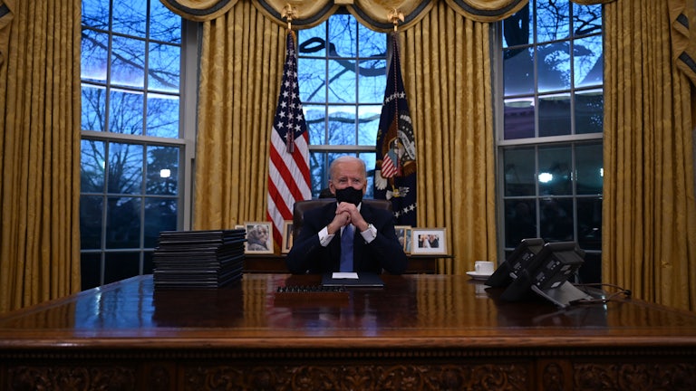 President Joe Biden sits behind his desk in the Oval Office.