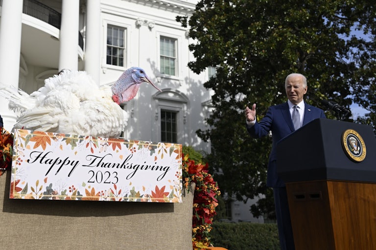 President Biden stands at a podium pointing to a turkey.