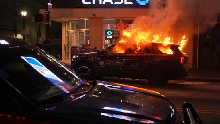 A police cruiser burns in front of a Chase bank.