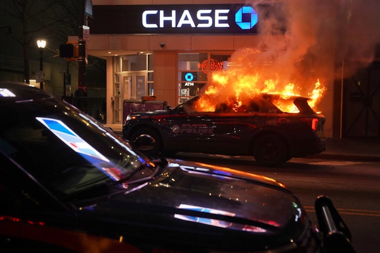 A police cruiser burns in front of a Chase bank.