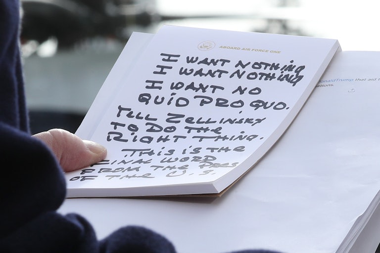 Donald Trump clutching a notepad with “I want nothing” and “I want no quid pro quo” written on it in large capitalized letters