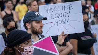 A protester holds a sign saying "vaccine equity now!"