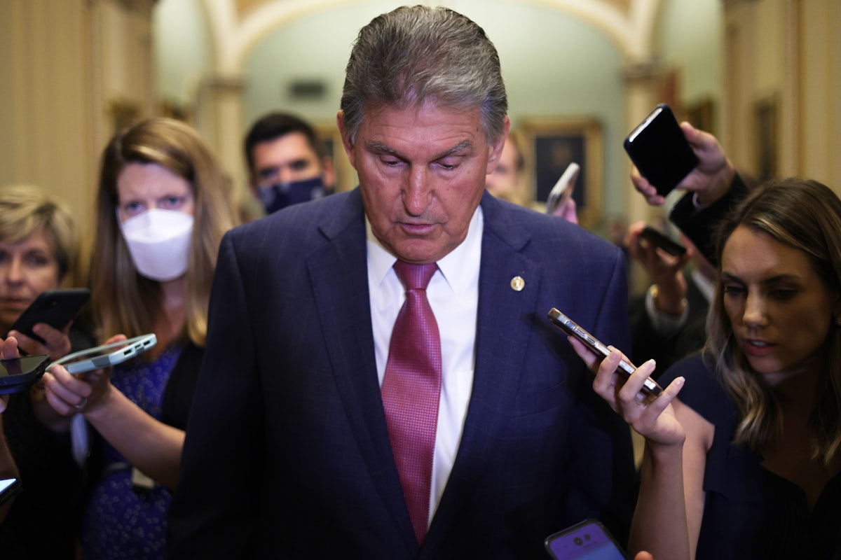 West Virginai Senatro Joe Manchin glances downward as he's trailed by reporters through Capitol Hill.
