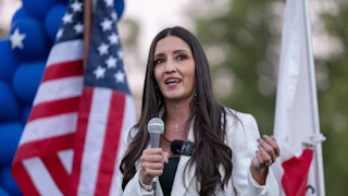 Sonja Shaw speaks with an American flag in the background.