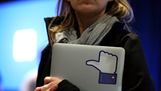 A Facebook employee holds a laptop with a "like" sticker on it.