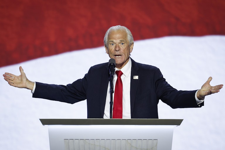 Peter Navarro speaks at a lectern and spreads his arms out as if to make a point. He looks stressed or worried.