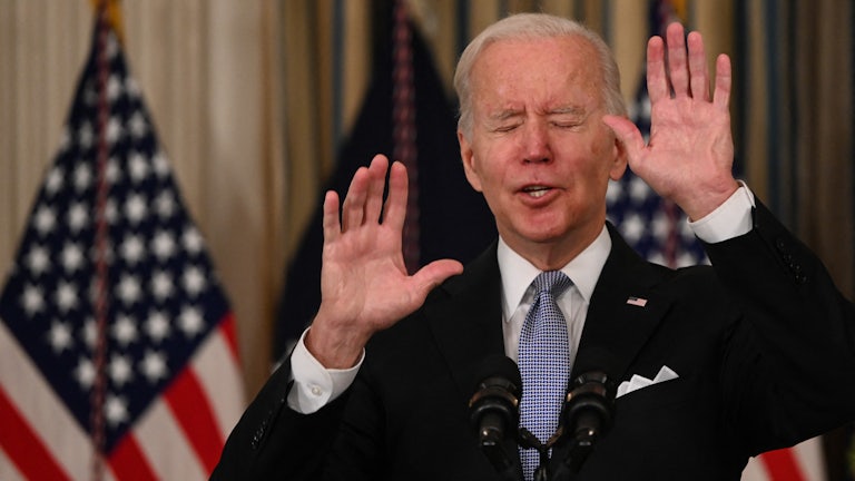 President Biden gestures with both hands while closing his eyes.