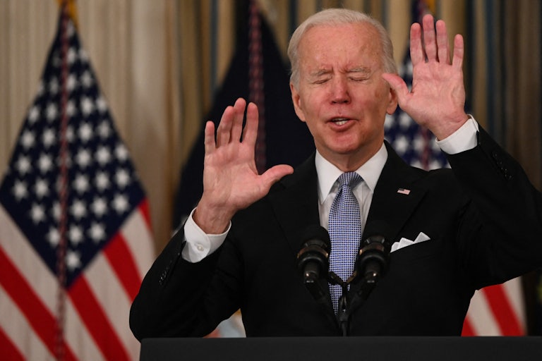 President Biden gestures with both hands while closing his eyes.
