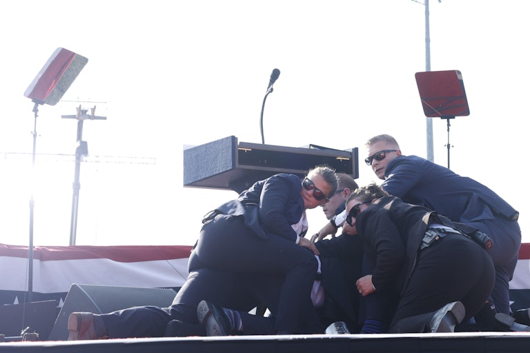 Donald Trump is covered by Secret Service on stage after the shooting