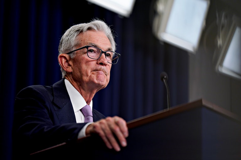 Federal Reserve Chair Jerome Powell frowns and grips the edge of a podium