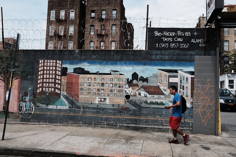 a man walks by a mural in the south bronx showing different types of housing