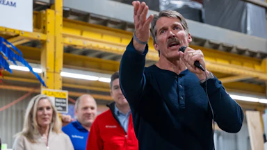 Wisconsin Republican Senate Candidate Eric Hovde speaking with a mic in his hand, as others look on