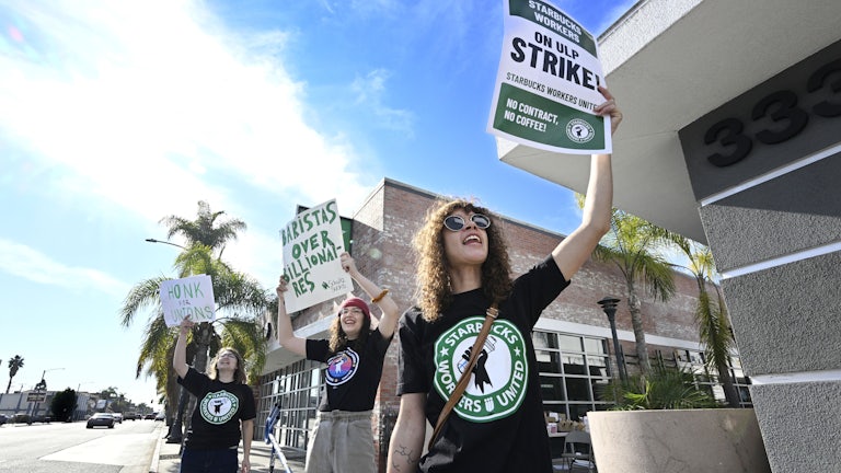 Starbucks workers protest with signs that read "Baristas over billionaires," "Honk for Unions," and "Starbucks Workers on ULP Strike."