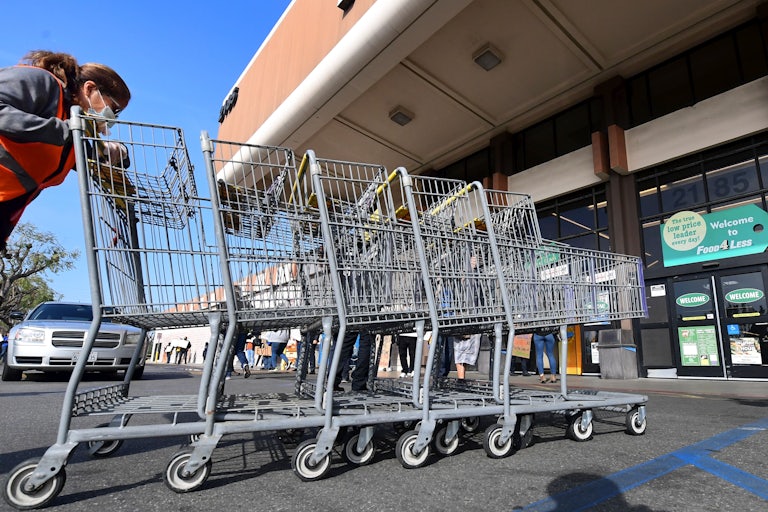 A Kroger's Food 4 Less employee pushes carts past protesting workers in Long Beach, California.